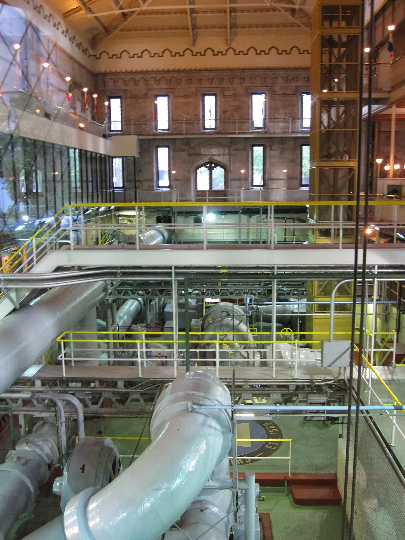 Interior of a municipal pumping station with large exposed pipes, pumps, and access platforms
